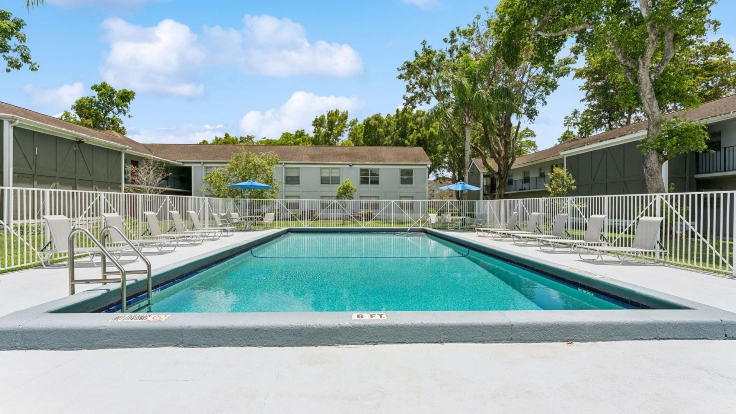 Inviting outdoor swimming pool surrounded by modern apartments and lush greenery, perfect for relaxation and leisure.