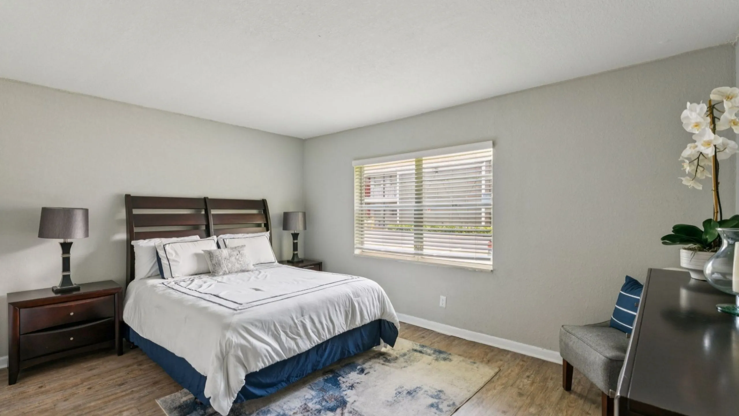 Elegant bedroom with modern decor, featuring a cozy bed, stylish lamps, and a large window for natural light.