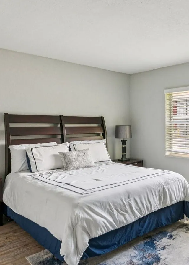 Bright and welcoming bedroom featuring a cozy wooden bed, elegant decor, and abundant natural light through large windows.