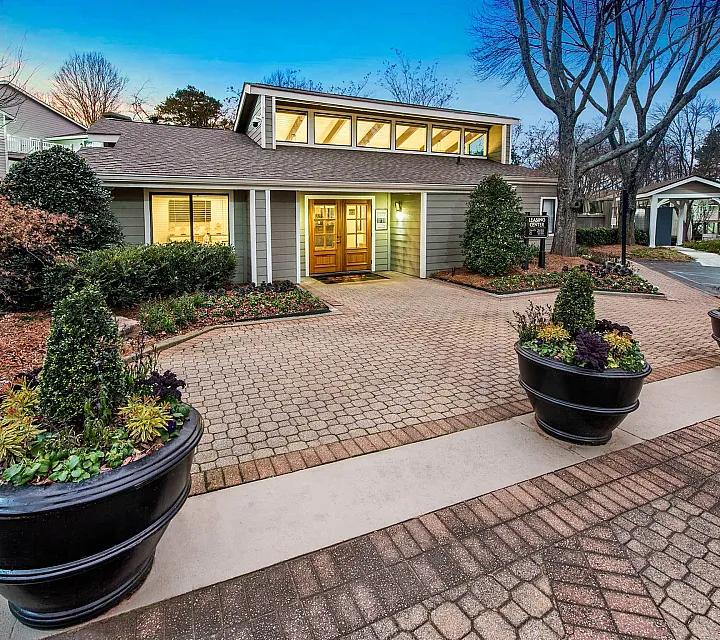 Charming exterior view of a modern apartment with landscaped entrance and elegant potted plants on a peaceful evening.