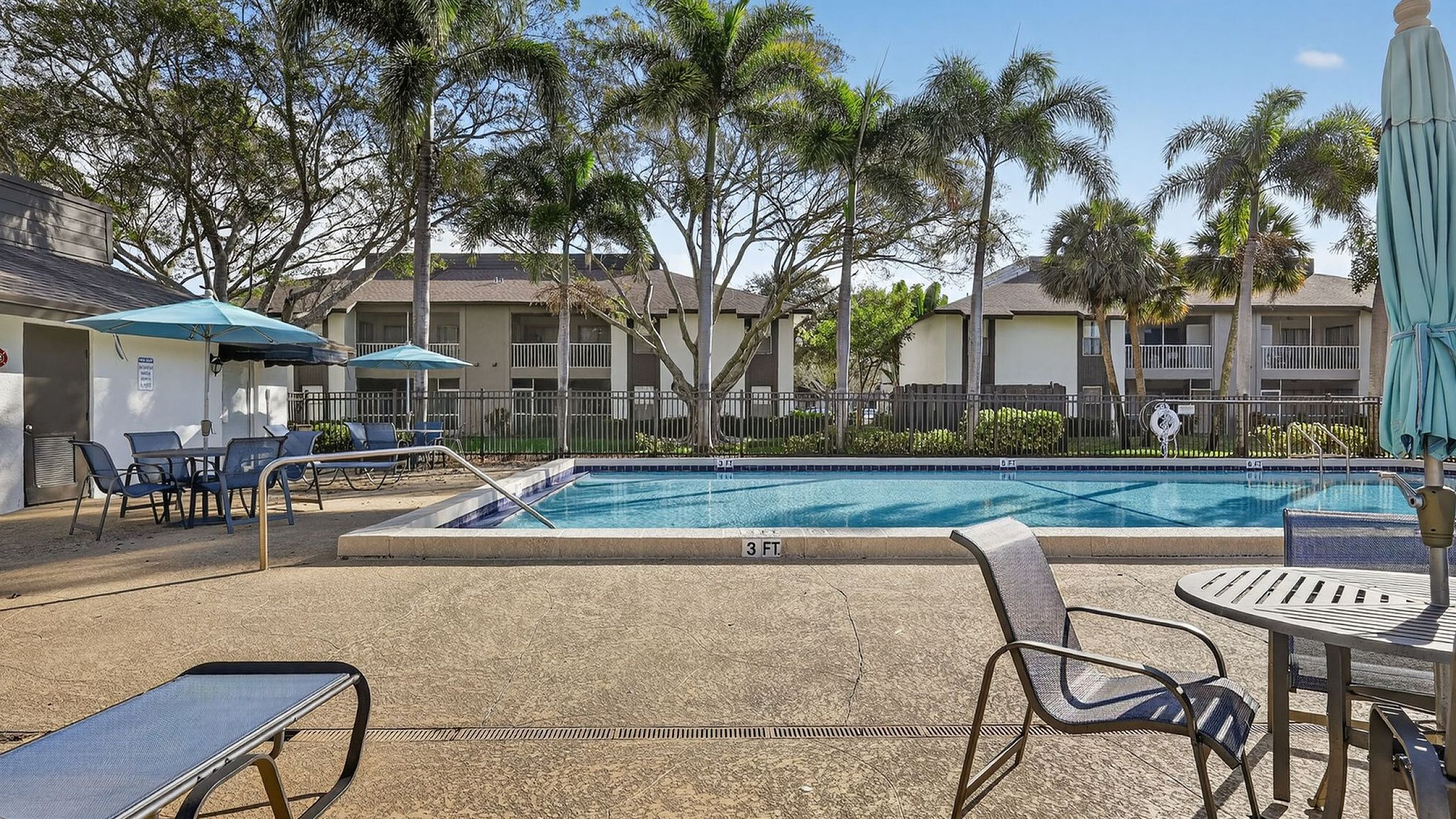 Inviting outdoor area showcasing a sparkling pool surrounded by lounge chairs and umbrellas, nestled in a lush, tropical setting.