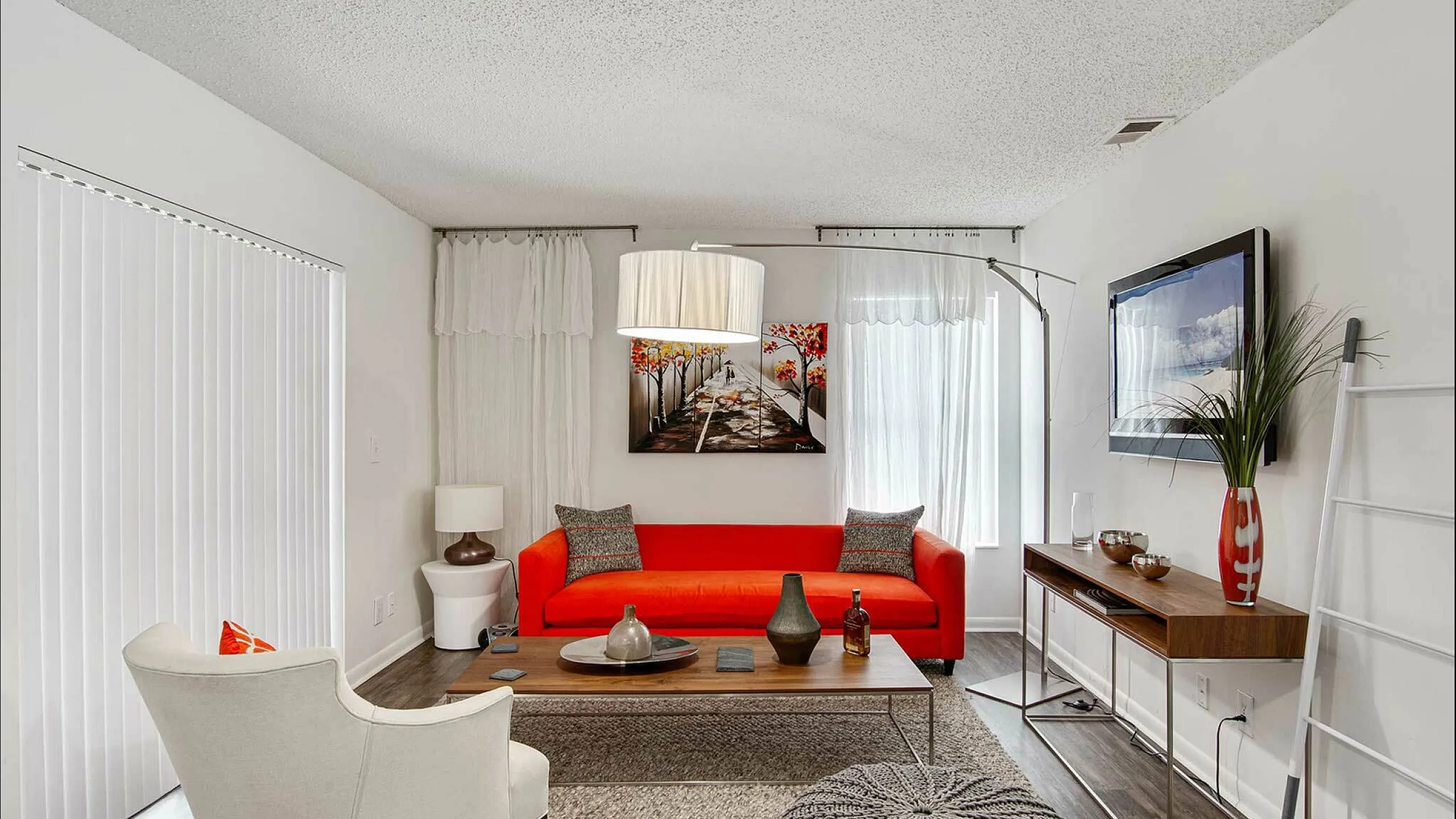 Modern living room with vibrant red sofa, elegant decor, and natural light creating a warm, inviting atmosphere.
