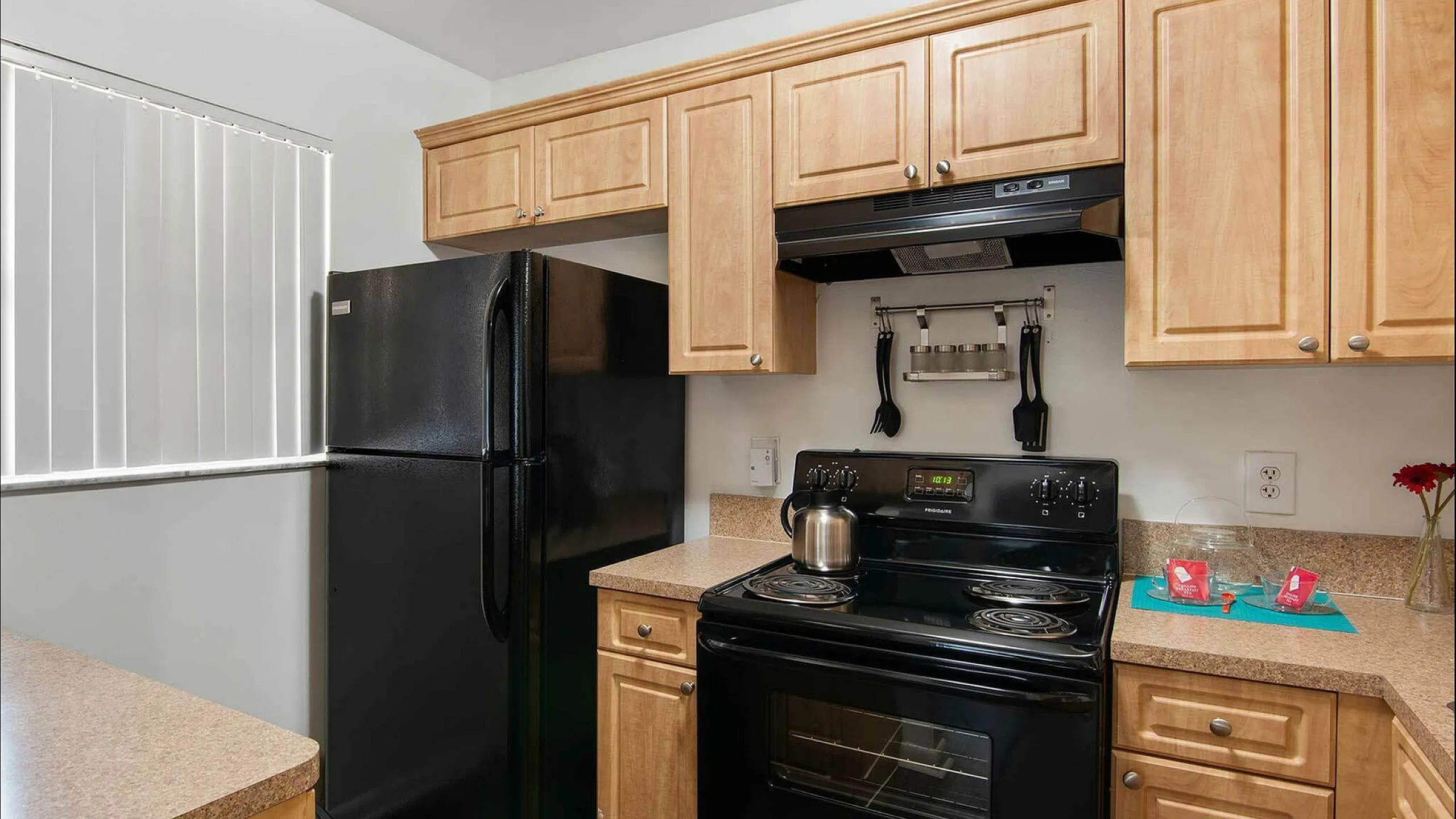 Modern kitchen featuring sleek black appliances, warm wooden cabinetry, and ample countertop space, ideal for culinary enthusiasts.