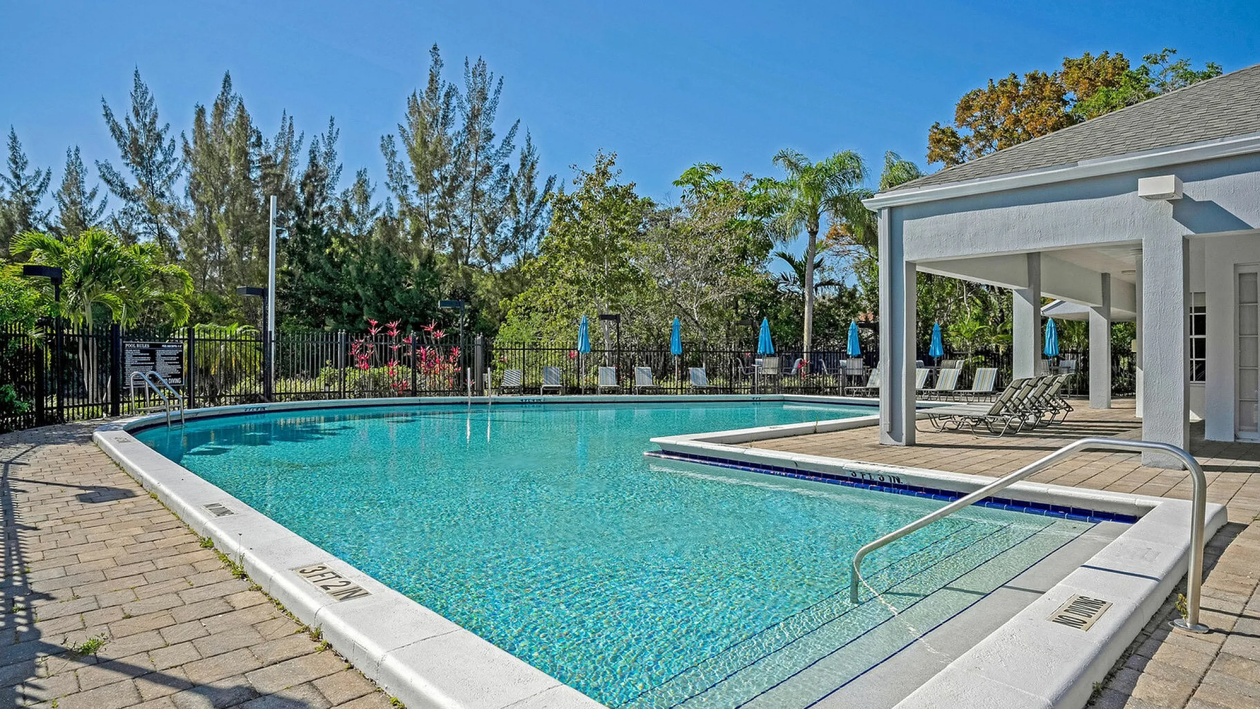 Luxurious outdoor pool area with crystal-clear water, surrounded by lush greenery and modern lounge chairs, perfect for relaxation and leisure.