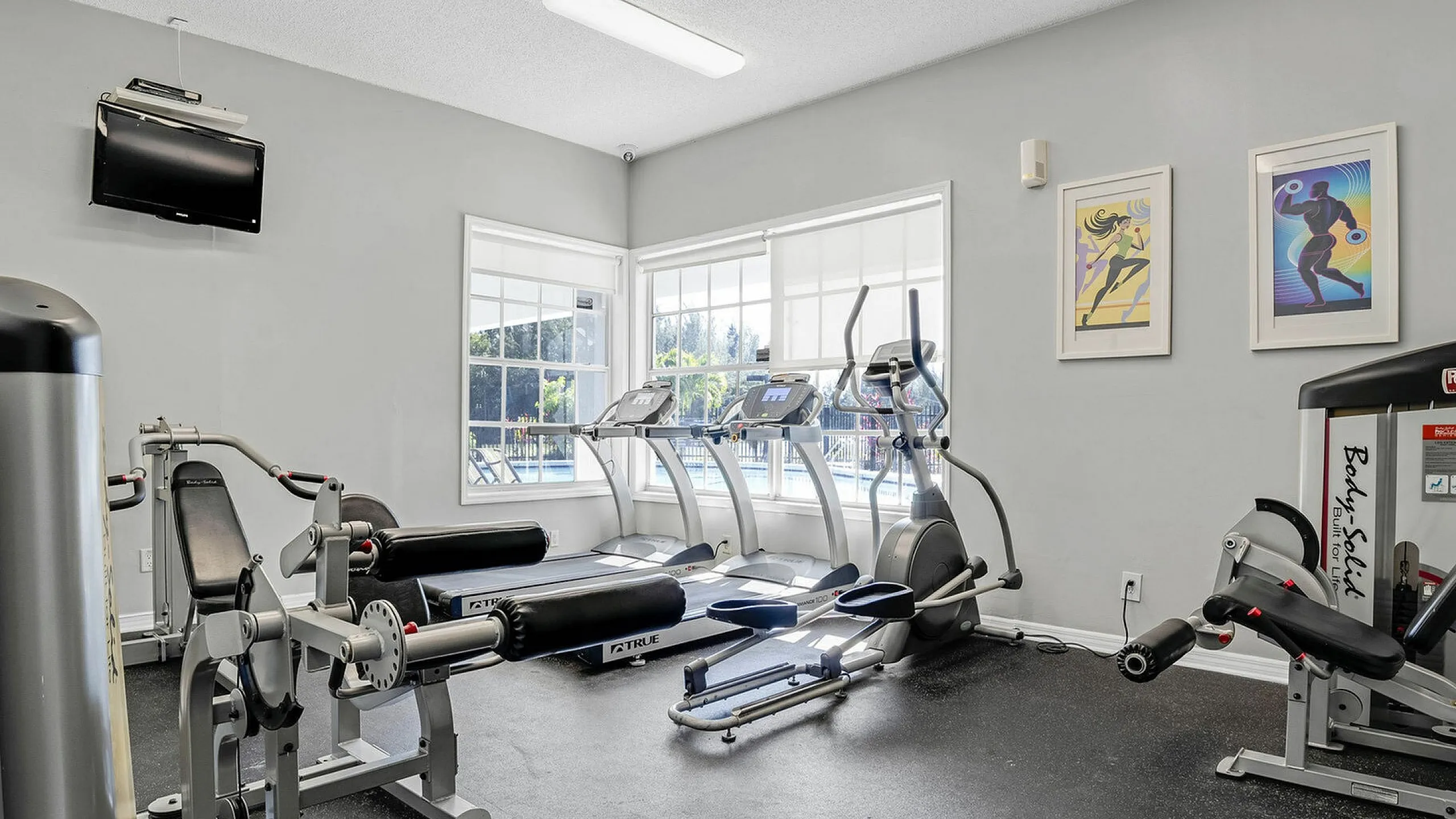 Bright and modern gym with top-of-the-line fitness equipment, large windows, and inspiring artwork for an energizing workout experience.