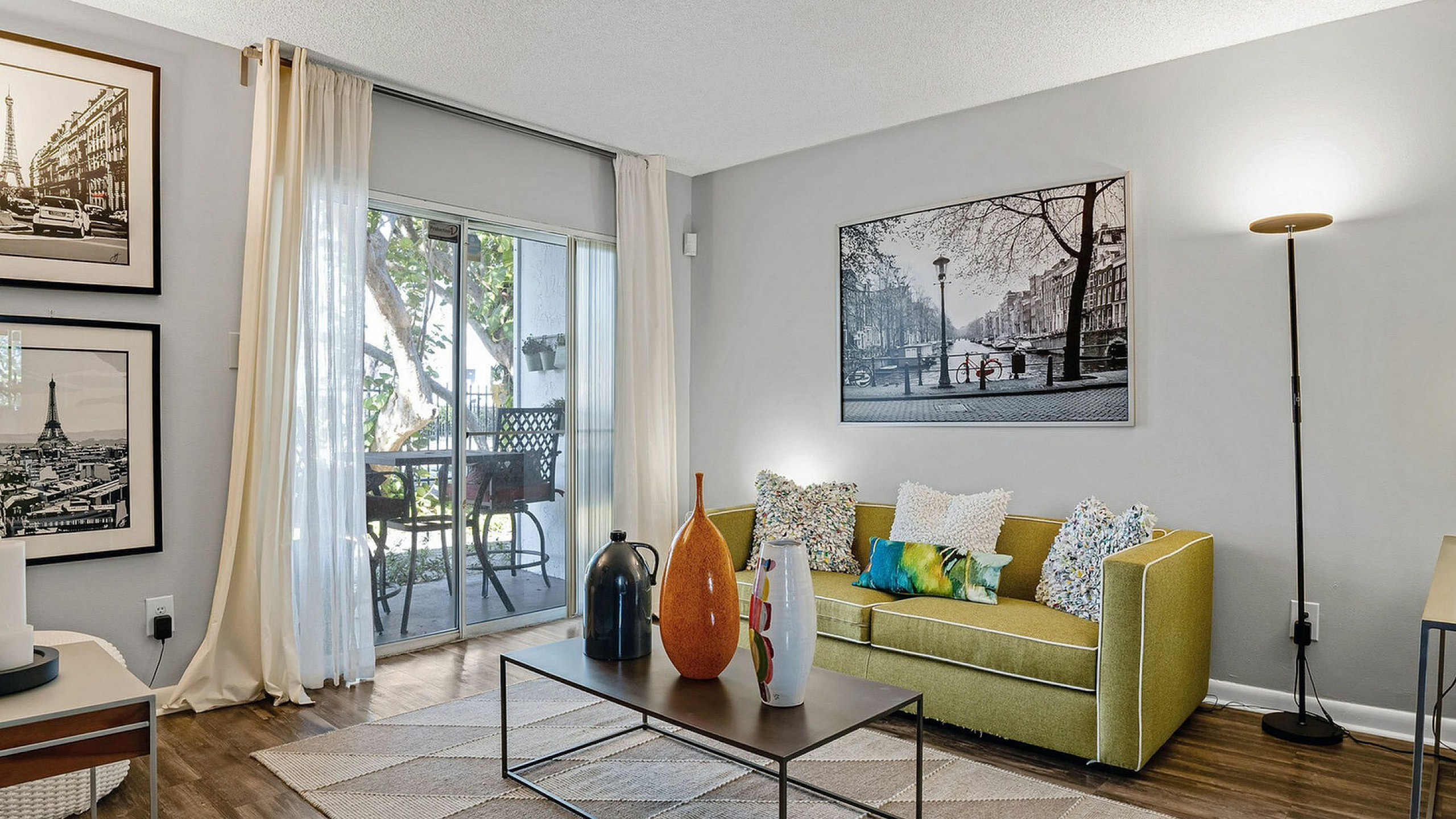 Inviting living room with a vibrant green sofa, artistic wall decor, and elegant sliding doors leading to a charming patio.