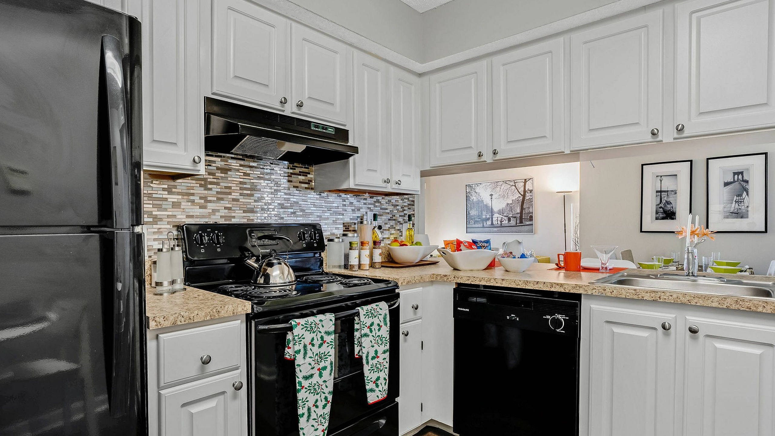 Modern kitchen with sleek black appliances, elegant white cabinetry, and a stylish mosaic backsplash, offering a chic and functional cooking space.