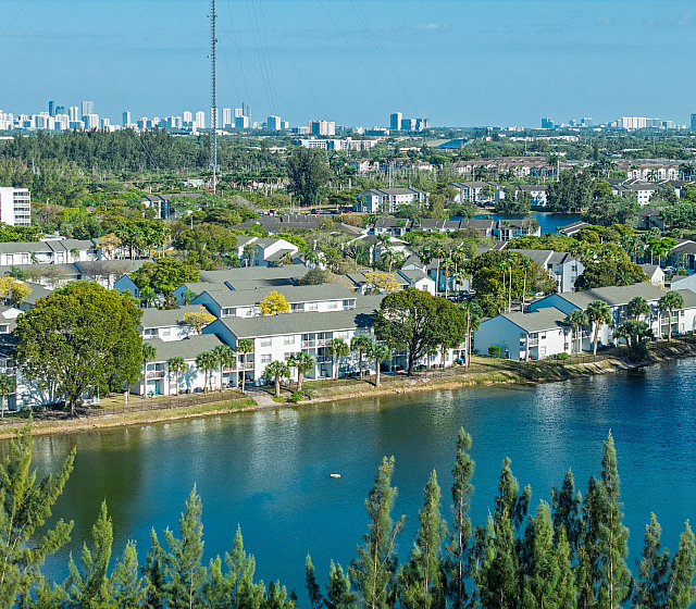 Breathtaking aerial view of a tranquil lakeside community surrounded by lush greenery and modern urban skyline.