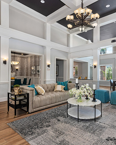 Luxurious living room with elegant high ceilings, a plush beige sofa, and stylish modern decor featuring vibrant blue and mustard accents in a spacious, light-filled setting.