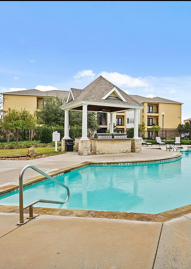 Inviting apartment community pool with elegant gazebo, surrounded by beautifully landscaped grounds.