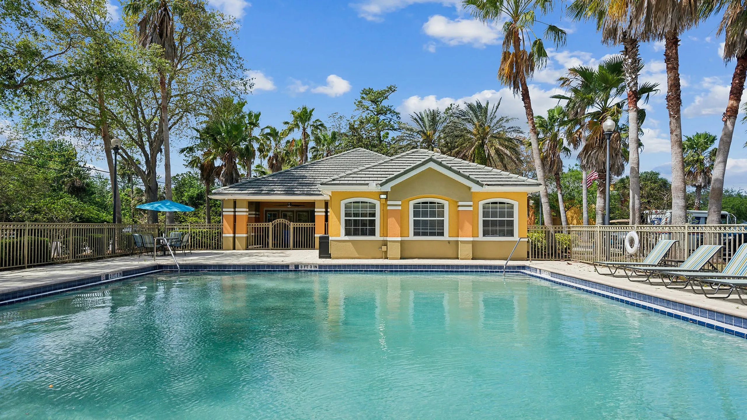Luxurious poolside retreat featuring a vibrant clubhouse and towering palm trees under a clear blue sky.