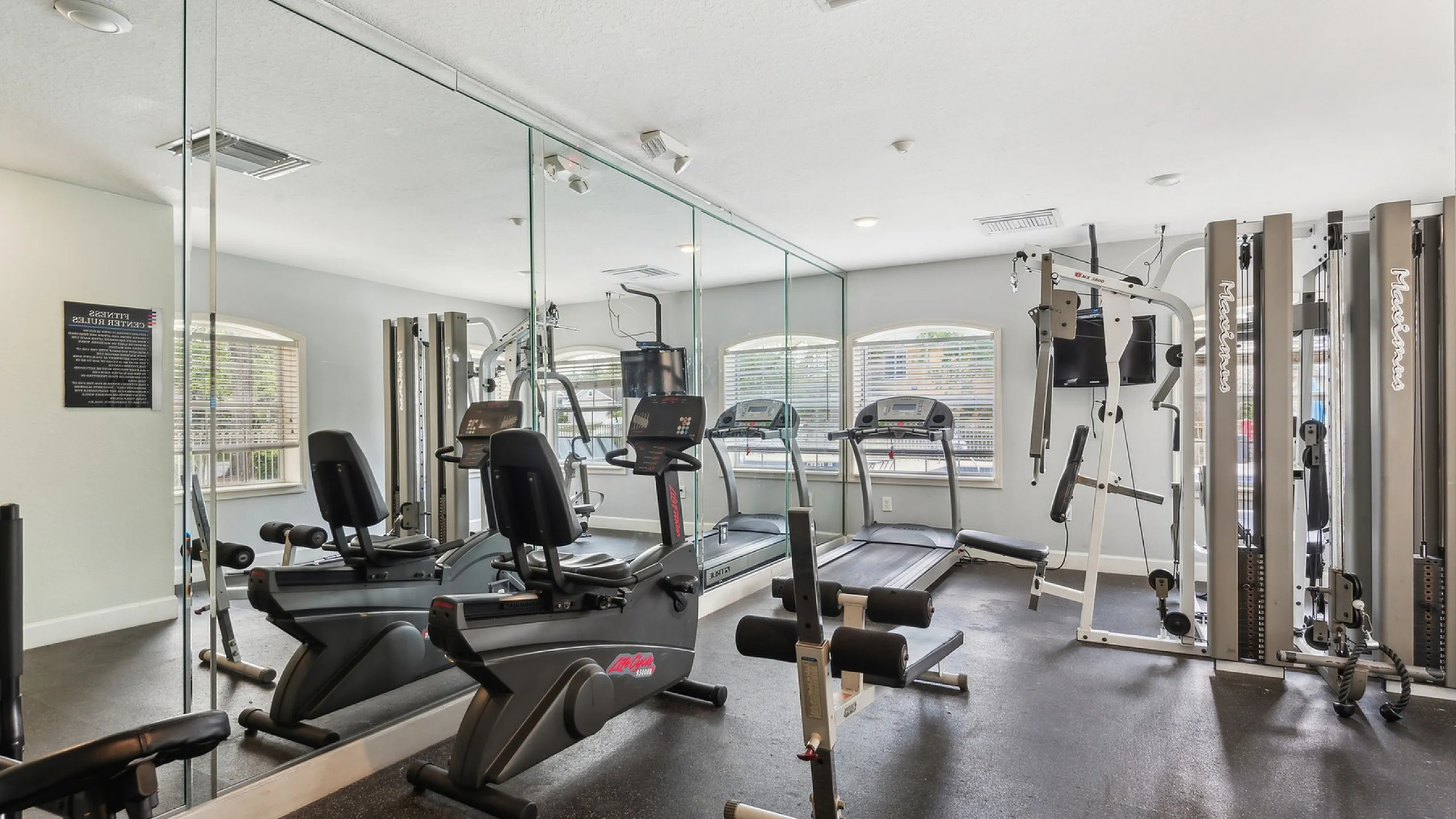 Modern fitness center with state-of-the-art gym equipment, mirrored walls, and bright natural lighting.