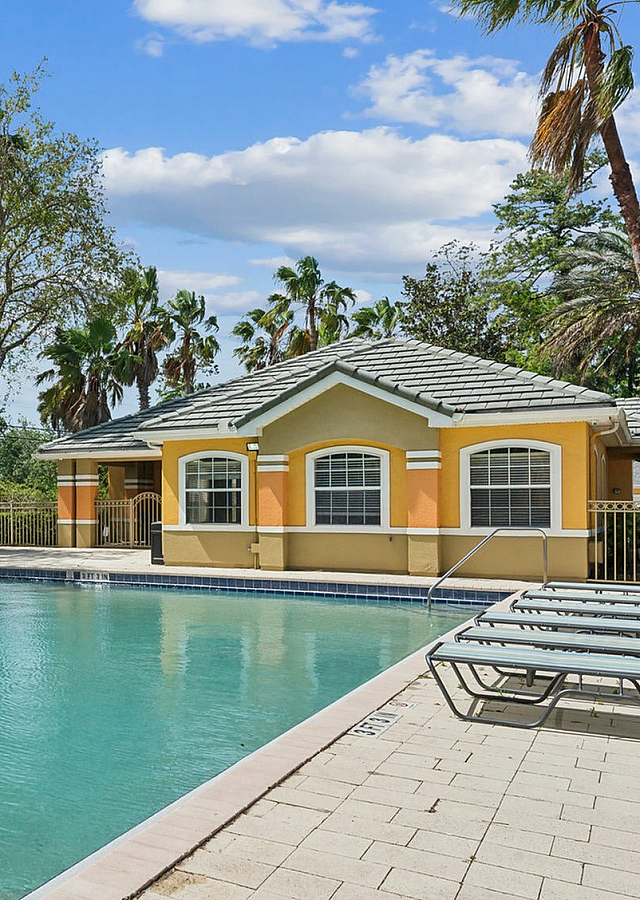 Inviting outdoor pool area surrounded by lush greenery, featuring comfortable lounge chairs and a charming cabana under a sunny sky.