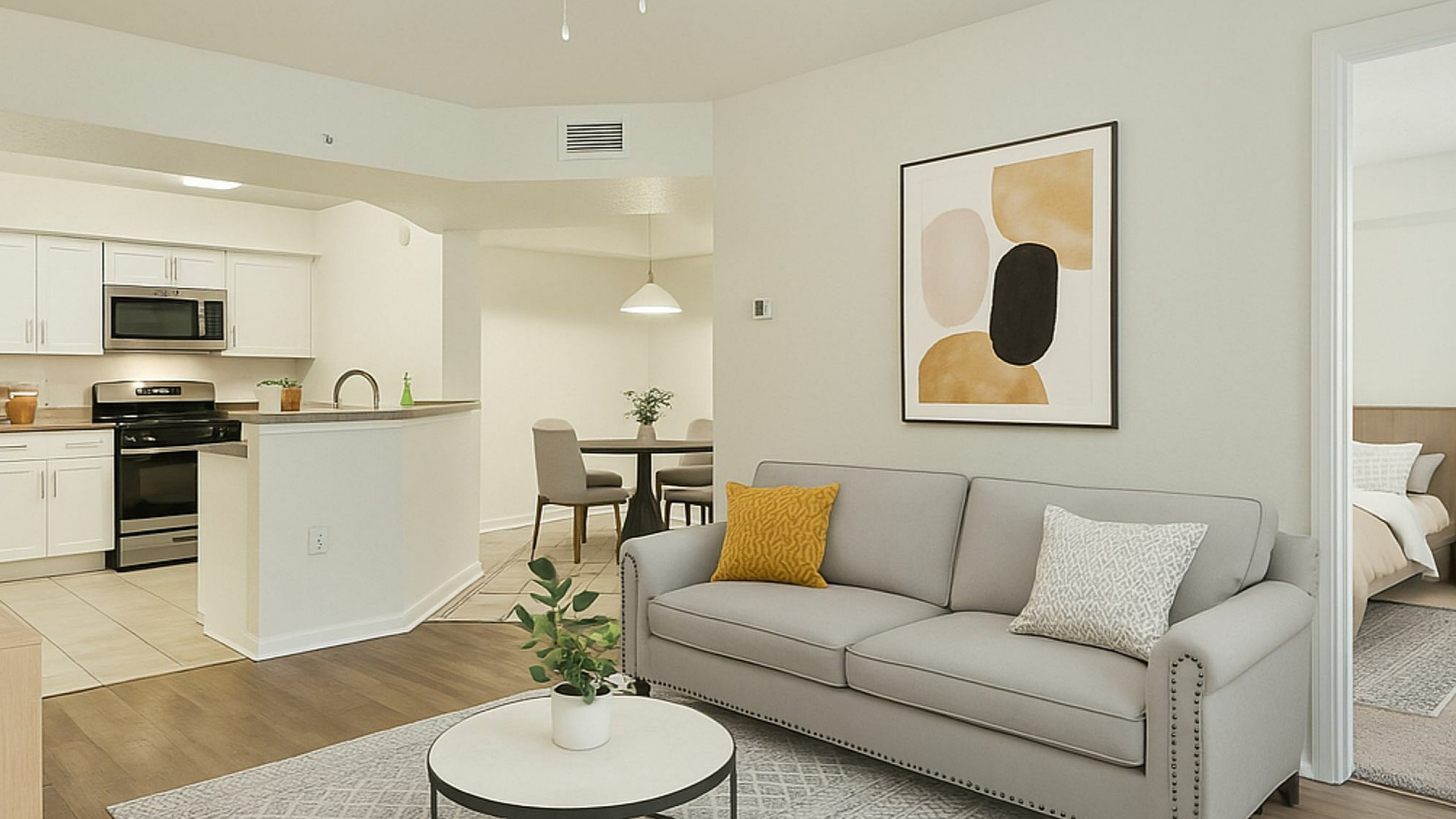 Contemporary open-concept living space with chic gray sofa, modern kitchen, and cozy dining area, ideal for comfort and style.