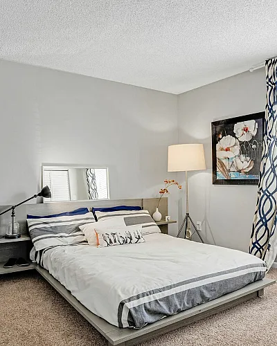 Elegant bedroom featuring a modern platform bed, cozy armchair, and stylish decor with abundant natural light.