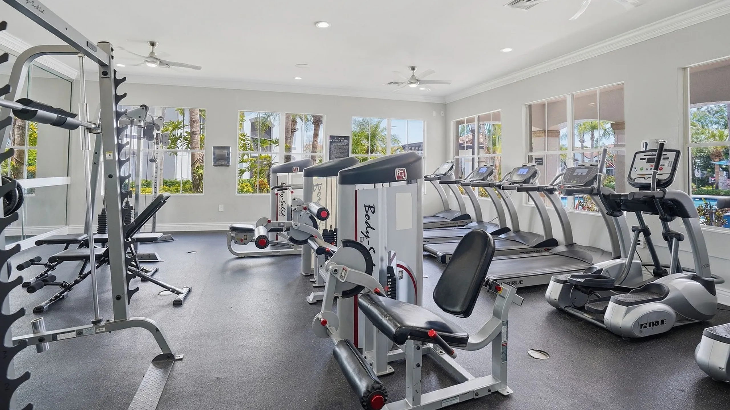 Modern fitness center with state-of-the-art equipment, including treadmills, weight machines, and a sunny window view.
