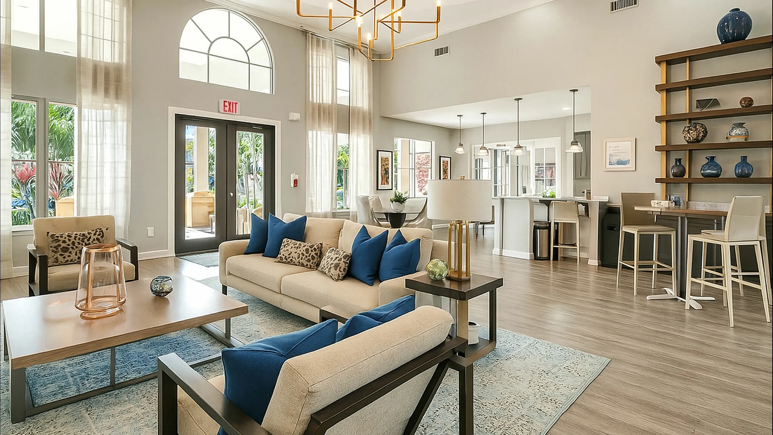 Elegant living area with high ceilings, modern chandelier, plush sofas, and abundant natural light flowing through large windows.