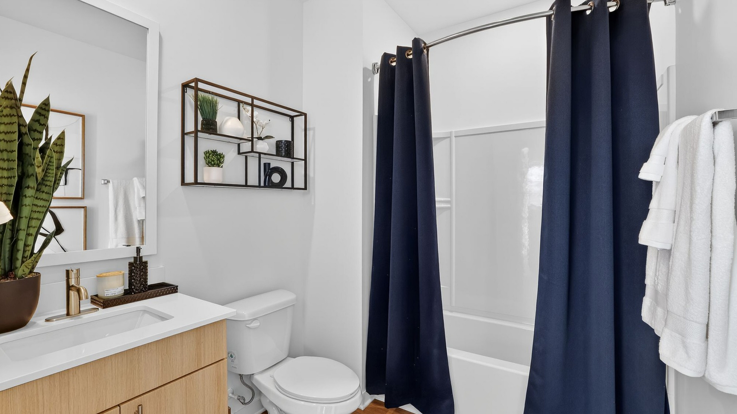 Contemporary bathroom featuring sleek vanity, modern shelving, and elegant navy blue shower curtains for a touch of sophistication.