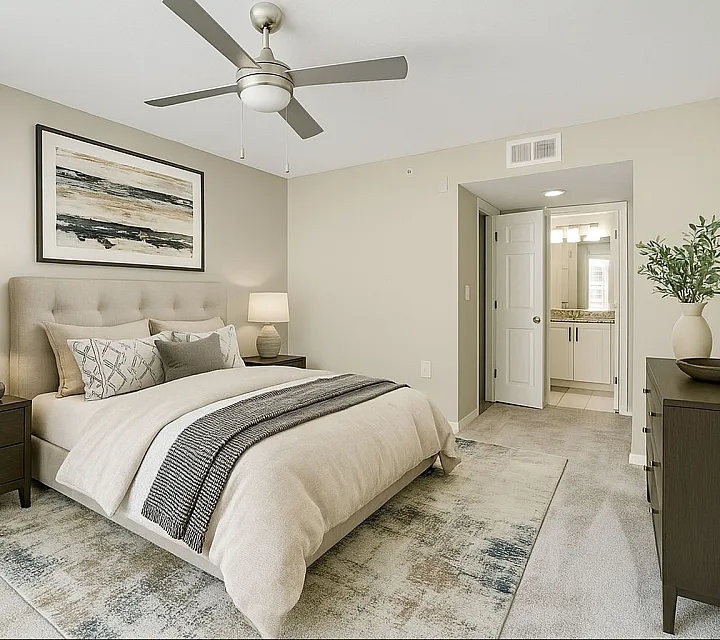 Elegant bedroom featuring a cozy bed with plush pillows, soft lighting, modern ceiling fan, and neutral d&eacute;cor opening to a luxurious ensuite bathroom.
