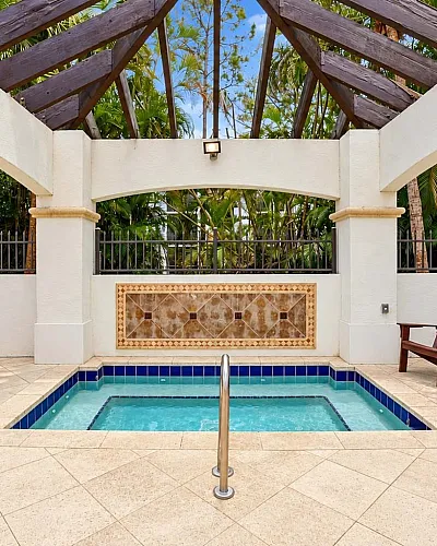 Charming outdoor space featuring a luxurious hot tub surrounded by elegant wood accents and lush greenery, perfect for relaxation.