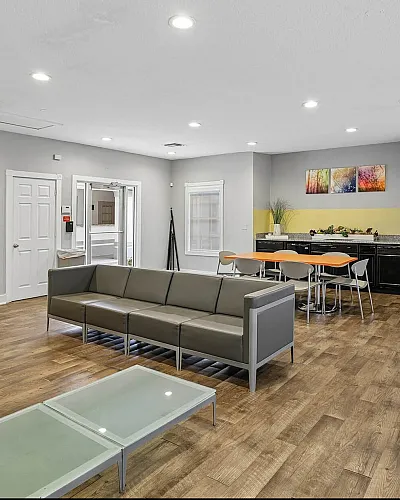 Modern community room with sleek seating, vibrant wall art, and a communal dining area, perfect for social gatherings.