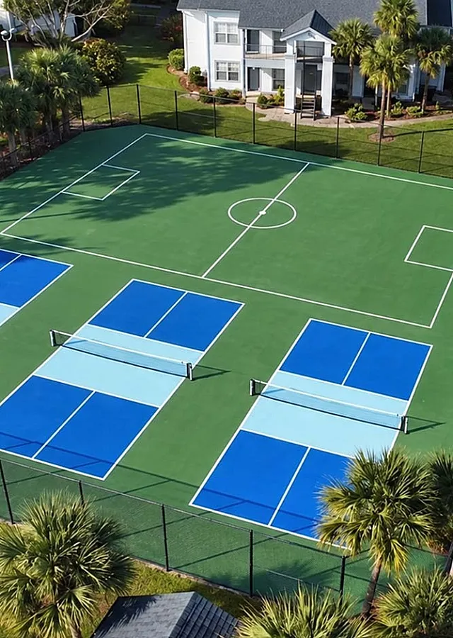Lush apartment community featuring modern recreational facilities, including vibrant blue tennis and sports courts, surrounded by well-maintained greenery and stylish residential buildings.