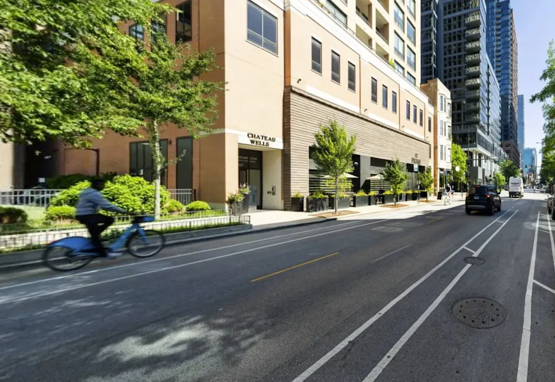 A street view of the exterior of Chateau on Wells, showcasing its modern architecture and prime location in the River North neighborhood of Chicago, with surrounding city streets and easy access to public transportation.