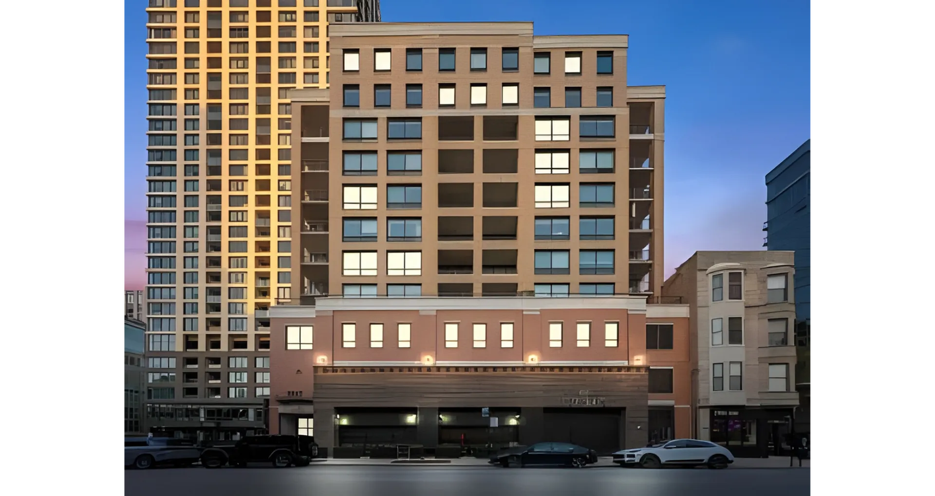 Modern urban apartment building with a sleek facade, featuring large windows and a well-lit entrance against a vibrant twilight sky.