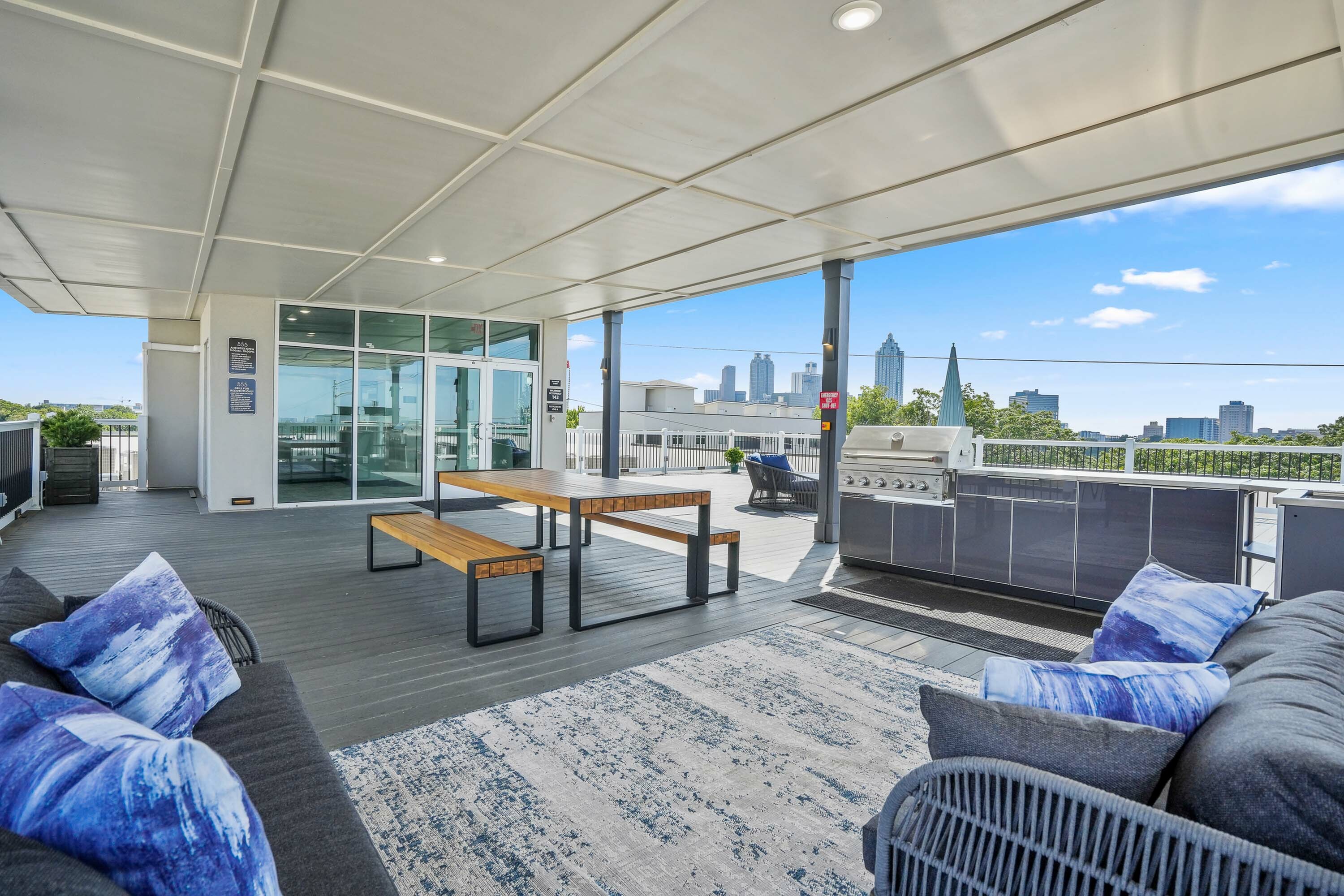 Modern rooftop patio with sleek outdoor kitchen, comfy seating, and panoramic city skyline views.