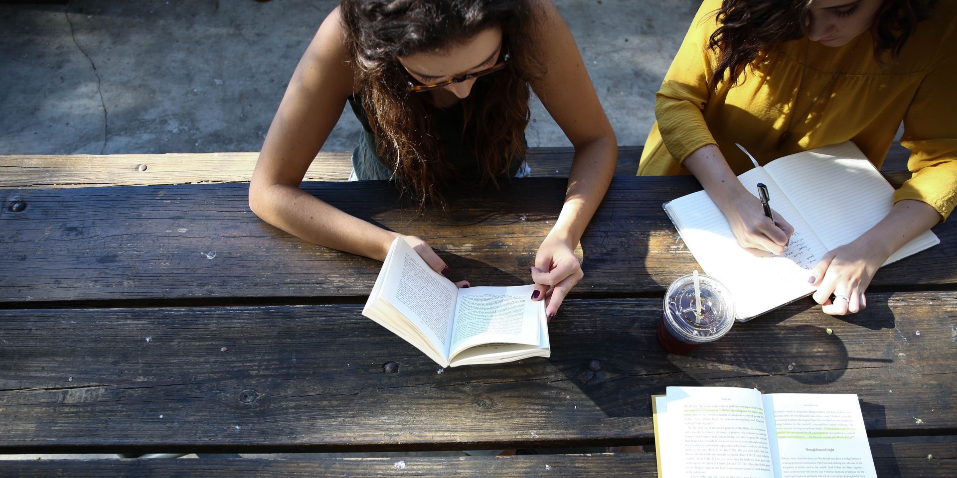 Stock Photo - Woman reading a book & another writing in a notebook sitting at a picnic table | The Timbers | Apartments in San Marcos, TX