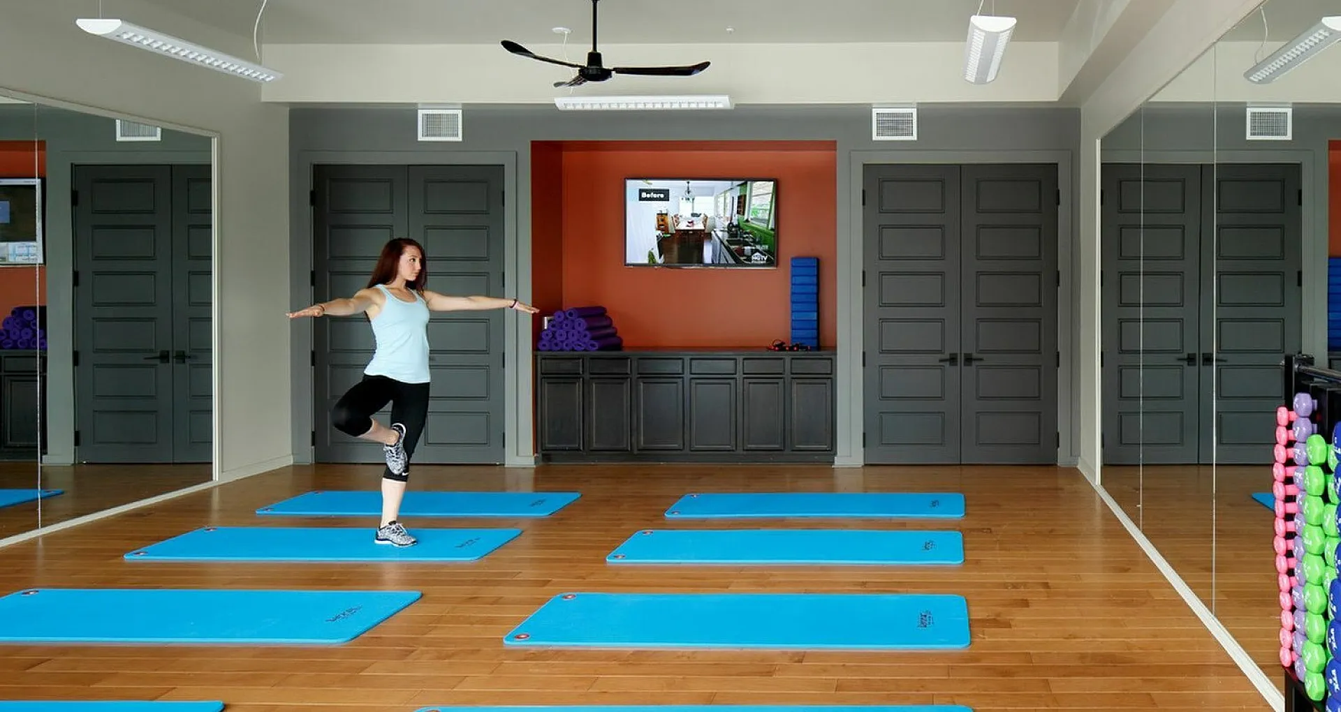 Bright fitness studio with yoga mats, mirrored walls, and workout equipment.