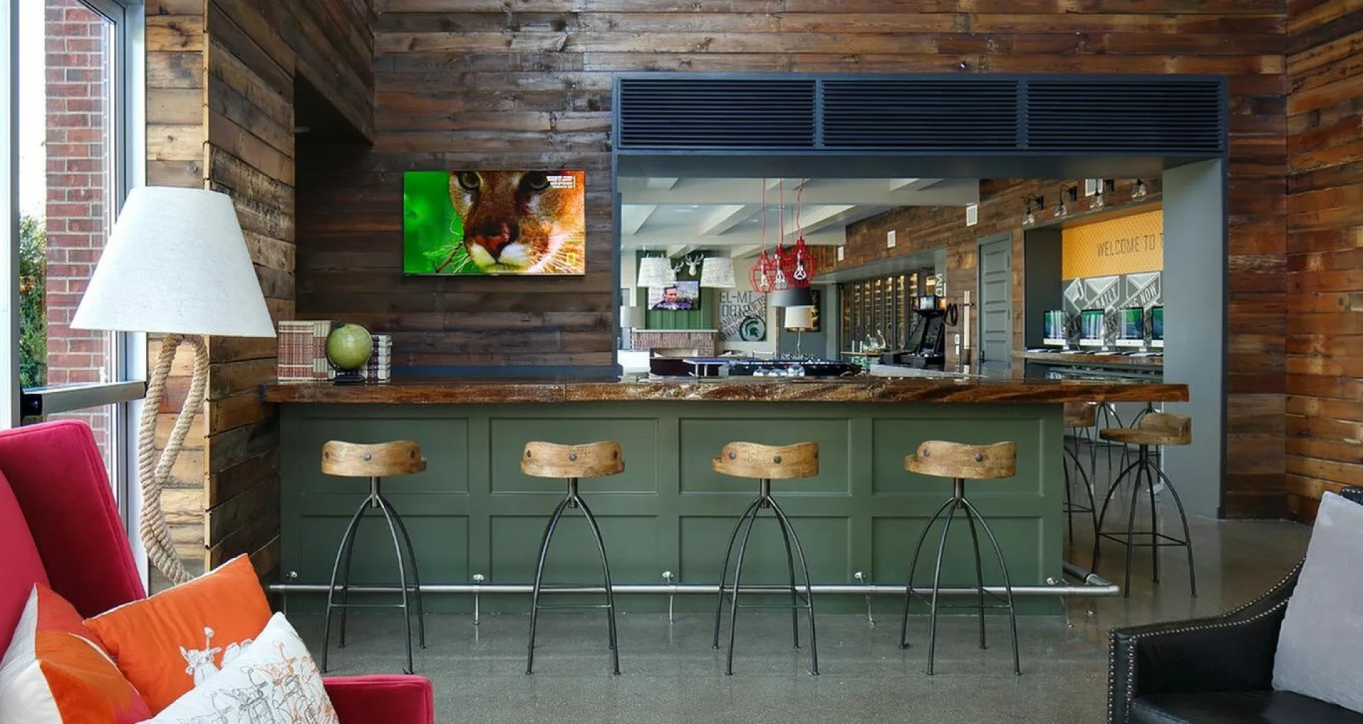 Contemporary lounge area featuring rustic wood paneling, a stylish bar with wooden stools, and vibrant seating.