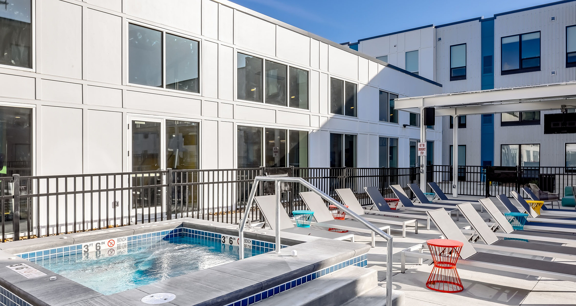 Sleek modern apartment exterior with inviting loungers and a refreshing hot tub.