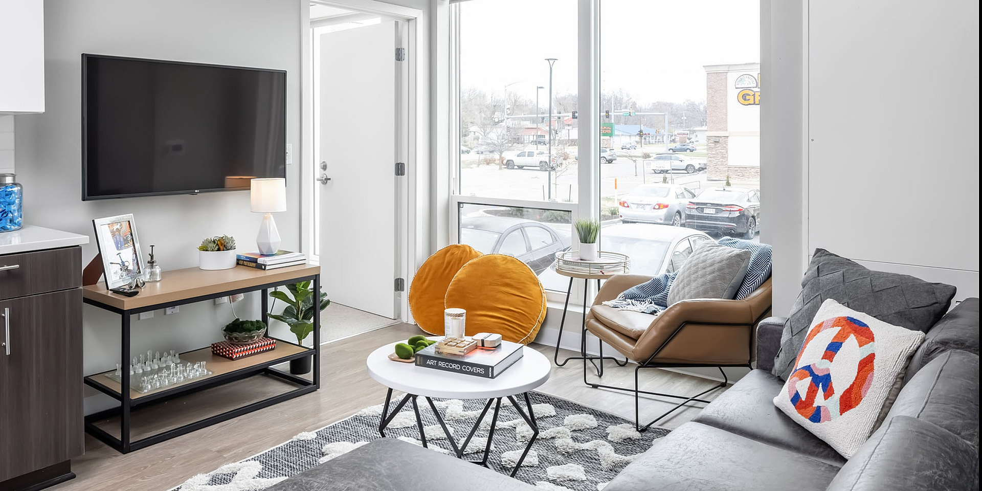 Bright and modern living room with a large window, sleek furniture, and stylish decor.