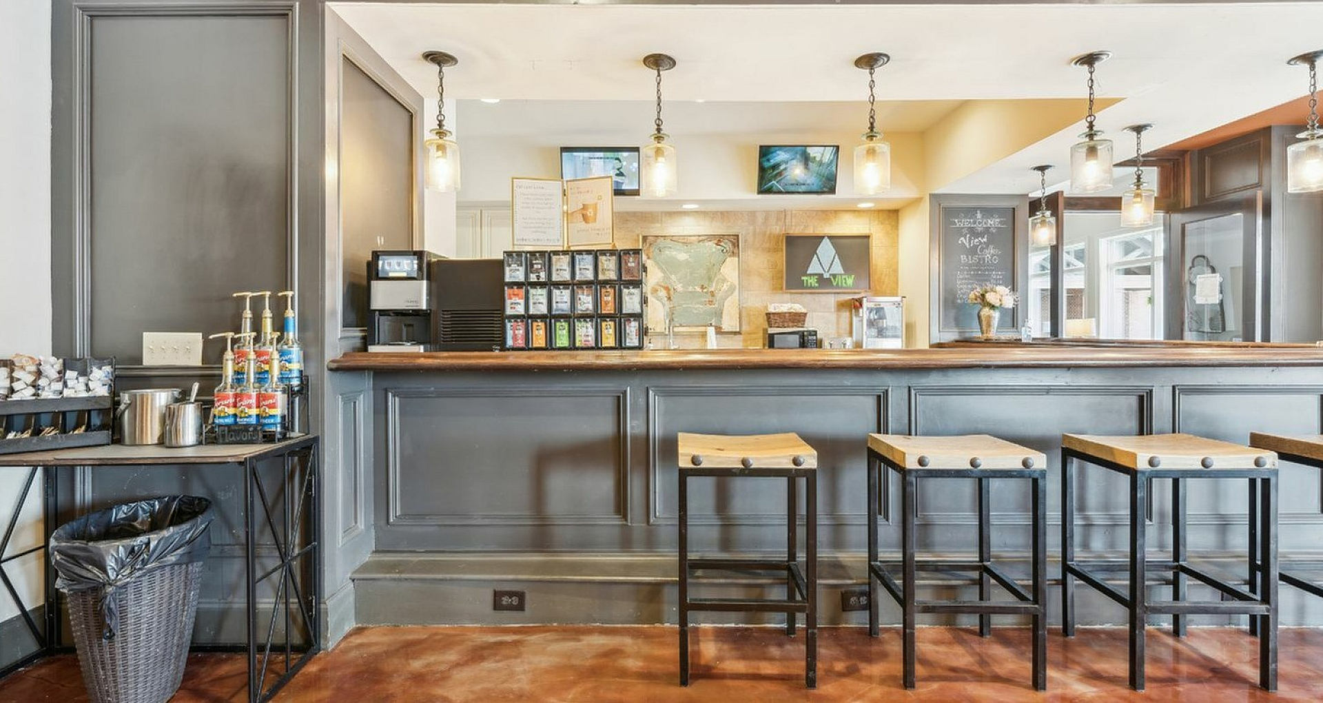 Elegant coffee bar with stylish high stools, warm lighting, and a variety of flavor options creating a cozy and inviting atmosphere.
