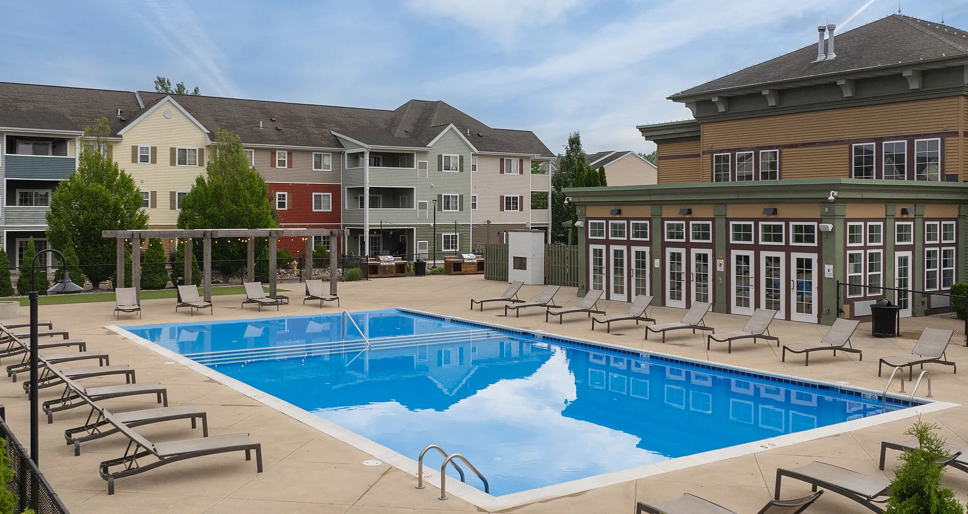 pool and sun deck with seating and shade umbrellas at 48 West Apartments in Allendale, MI