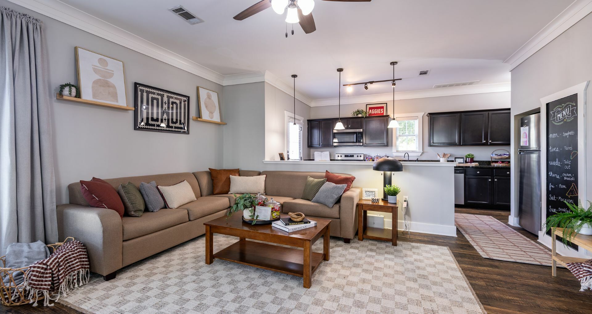 Charming open-concept living room with modern kitchen, cozy sectional sofa, vibrant decor, and stylish pendant lighting.