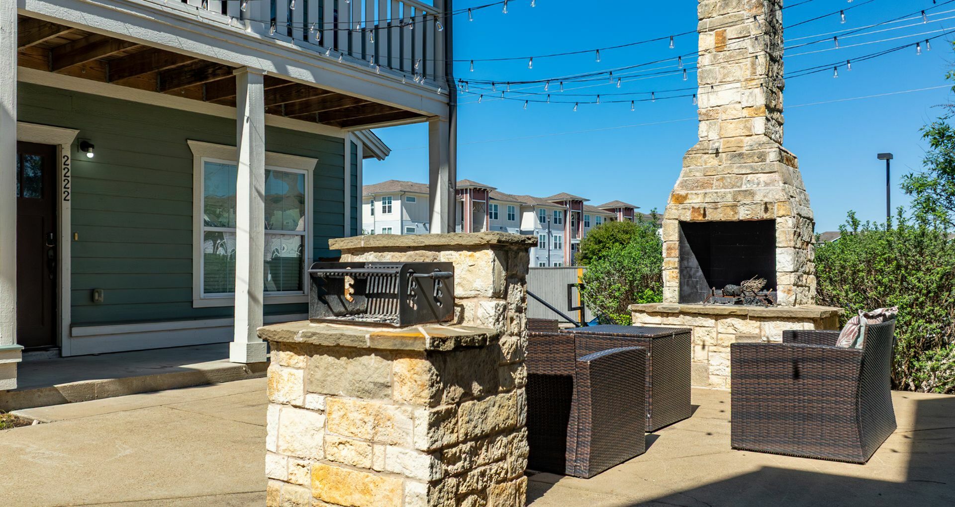 Inviting patio with a cozy stone fireplace and stylish outdoor seating, ideal for relaxation and entertaining in a vibrant community setting.