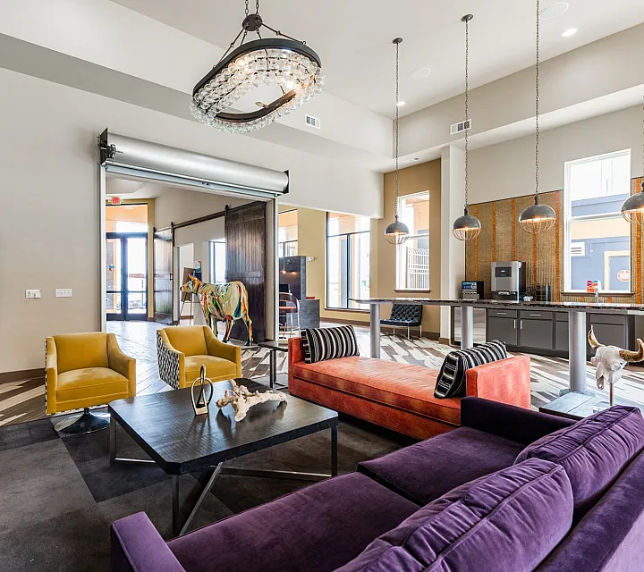 Modern communal lounge featuring vibrant seating, elegant chandelier, and stylish decor, ideal for relaxation and social gatherings.