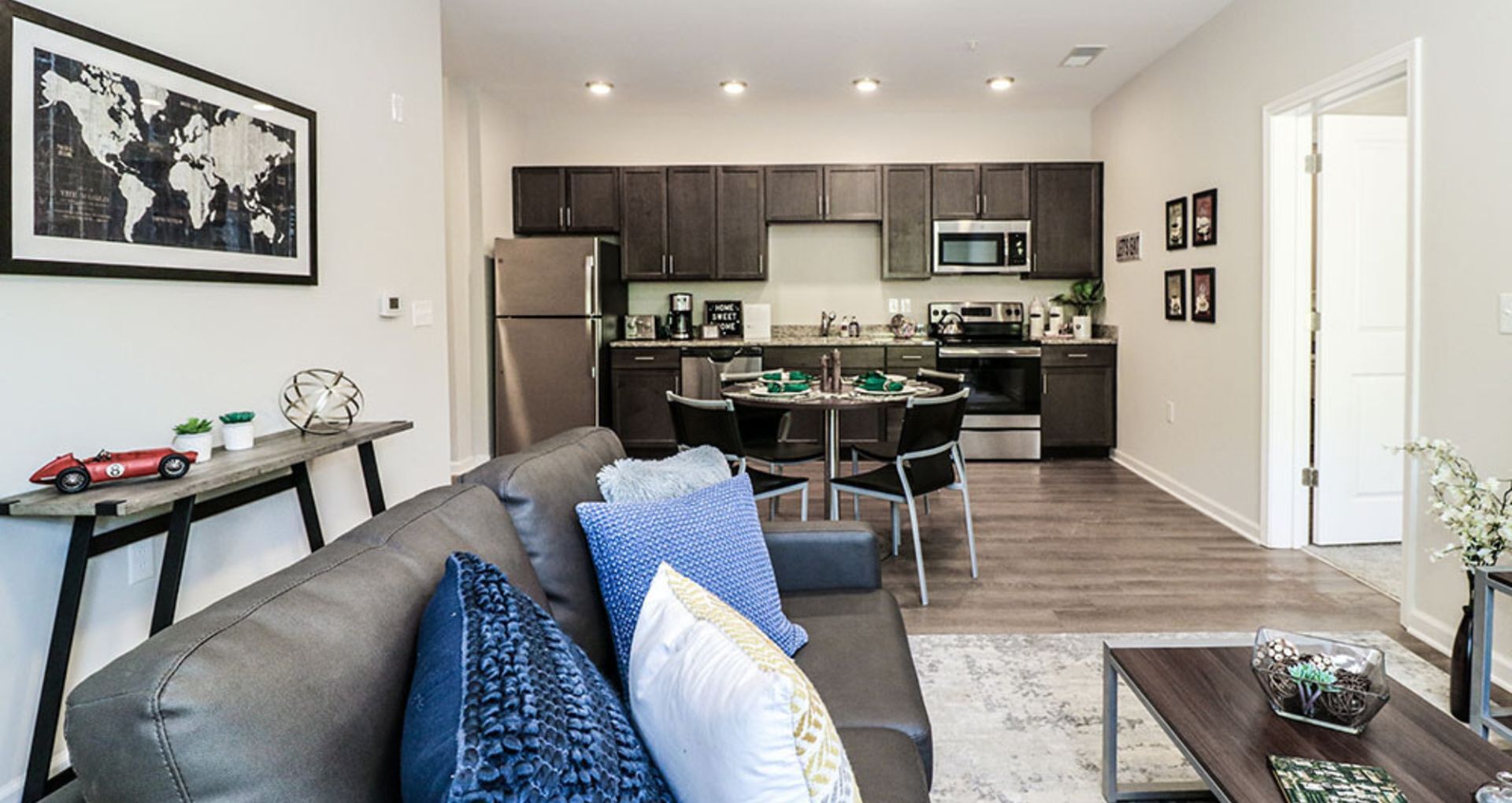 Modern open-concept living area featuring a stylish kitchen with dark cabinetry, elegant dining space, and a comfy seating area with chic decor.