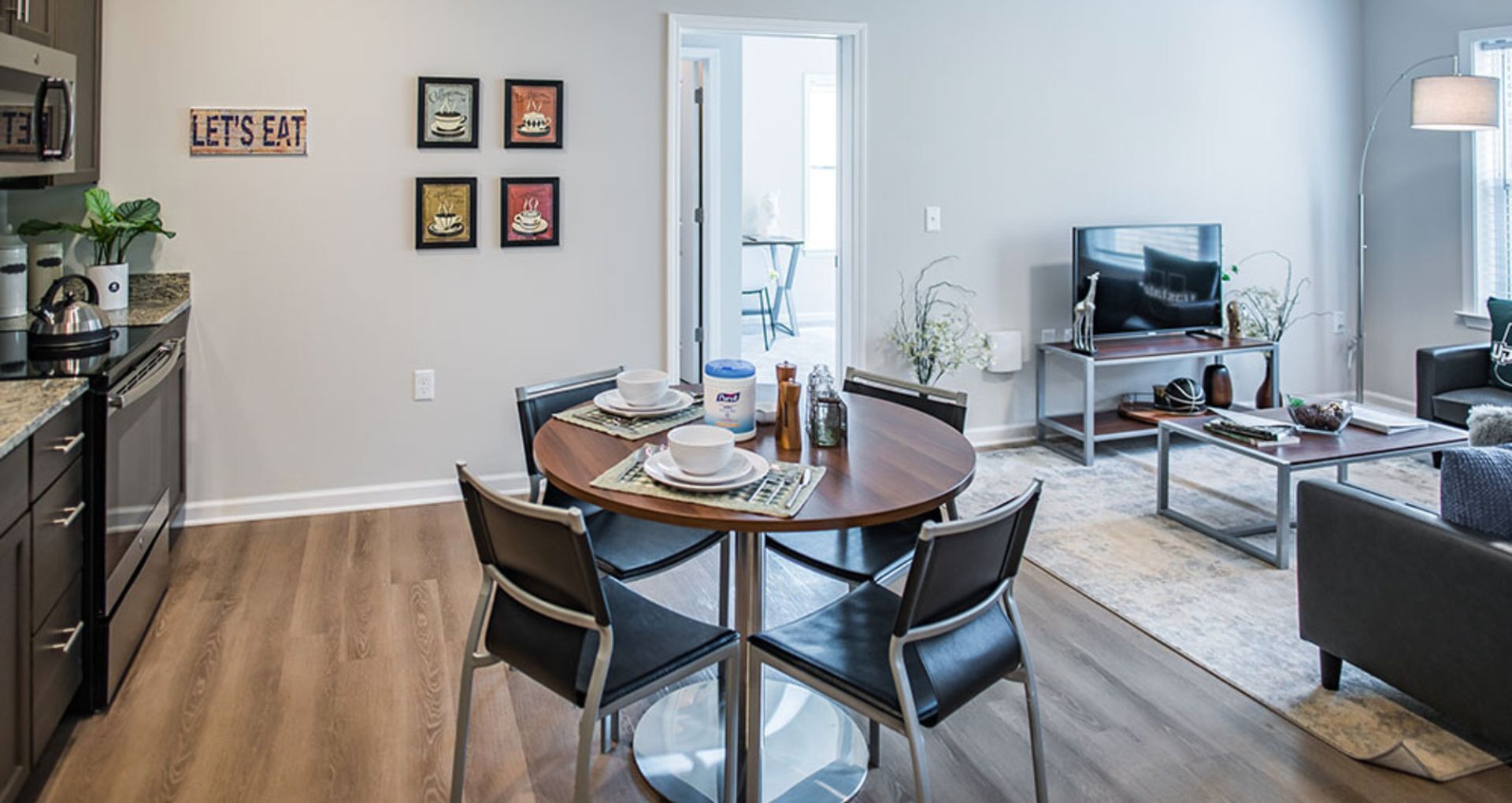 Modern apartment interior showcasing a cozy dining area with sleek furniture, stylish living room with a flat-screen TV, and elegant decor.