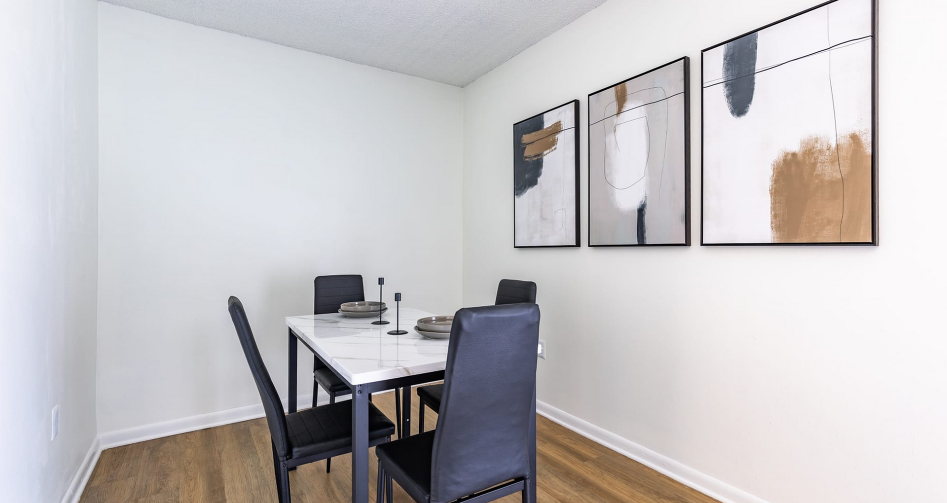 Elegant dining area with a sleek table, four modern black chairs, and abstract wall art, creating a sophisticated ambiance.