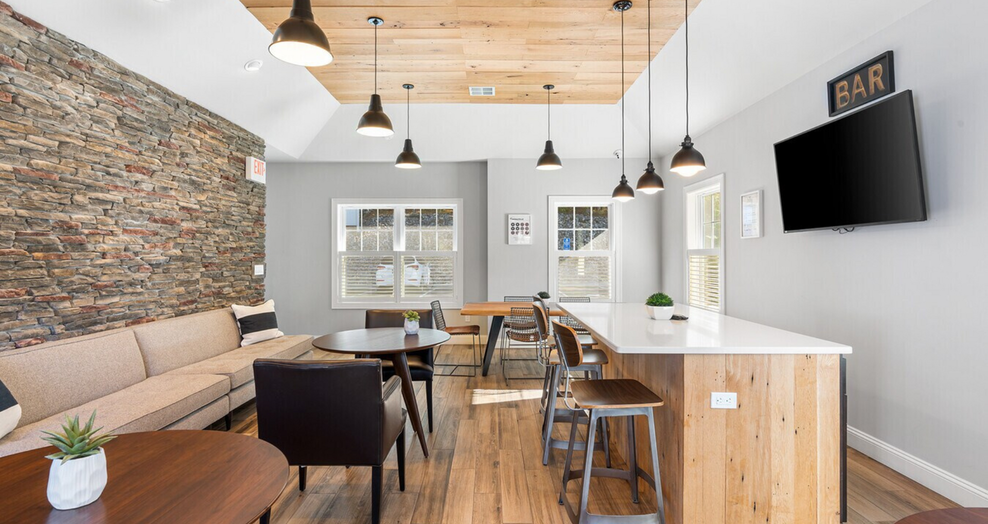 Chic communal lounge area featuring a modern stone accent wall, cozy seating, and stylish lighting, perfect for relaxation and social gatherings.