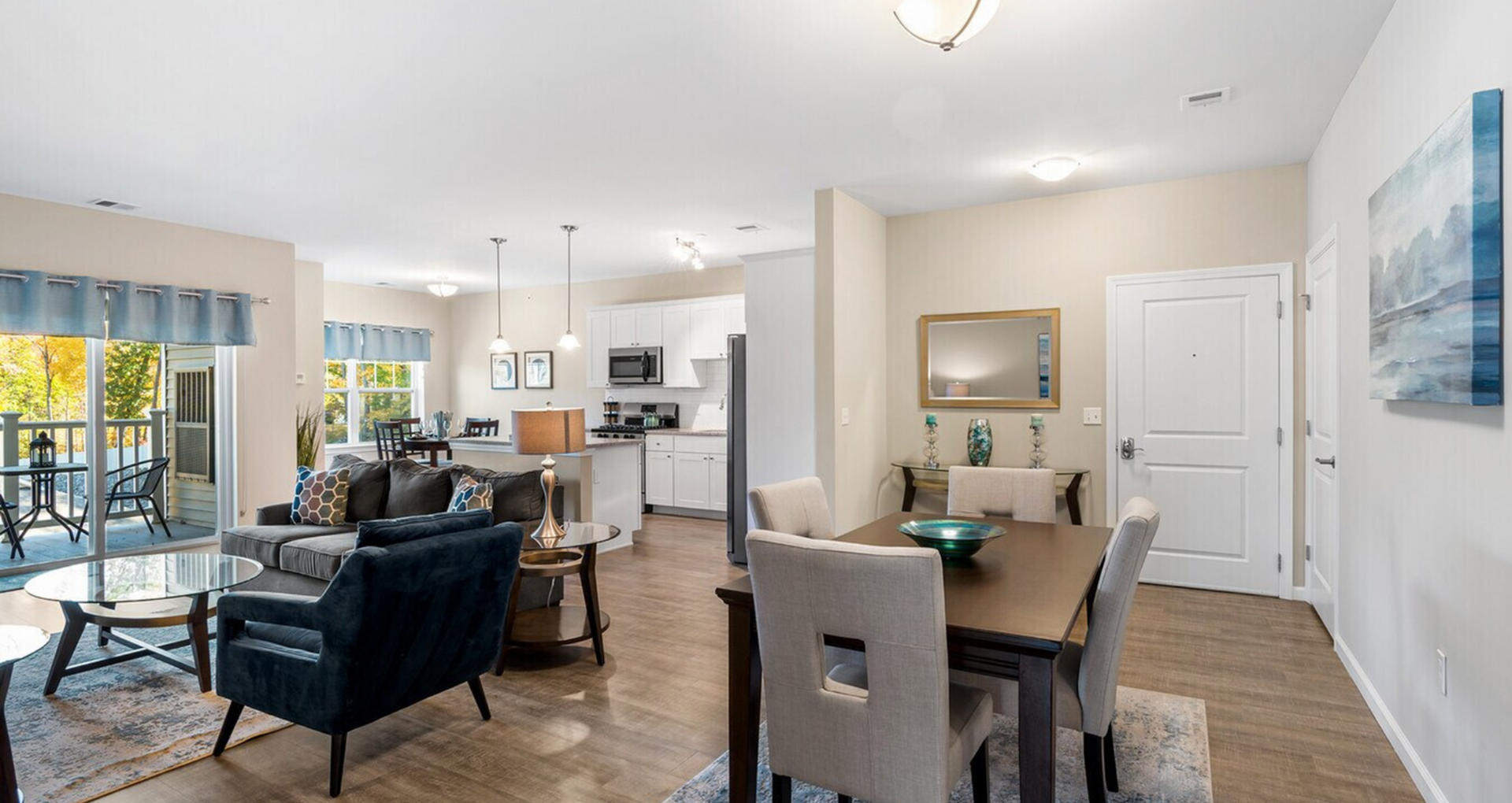 Bright and open-concept living and dining area with stylish decor, modern kitchen, and access to a cozy balcony.