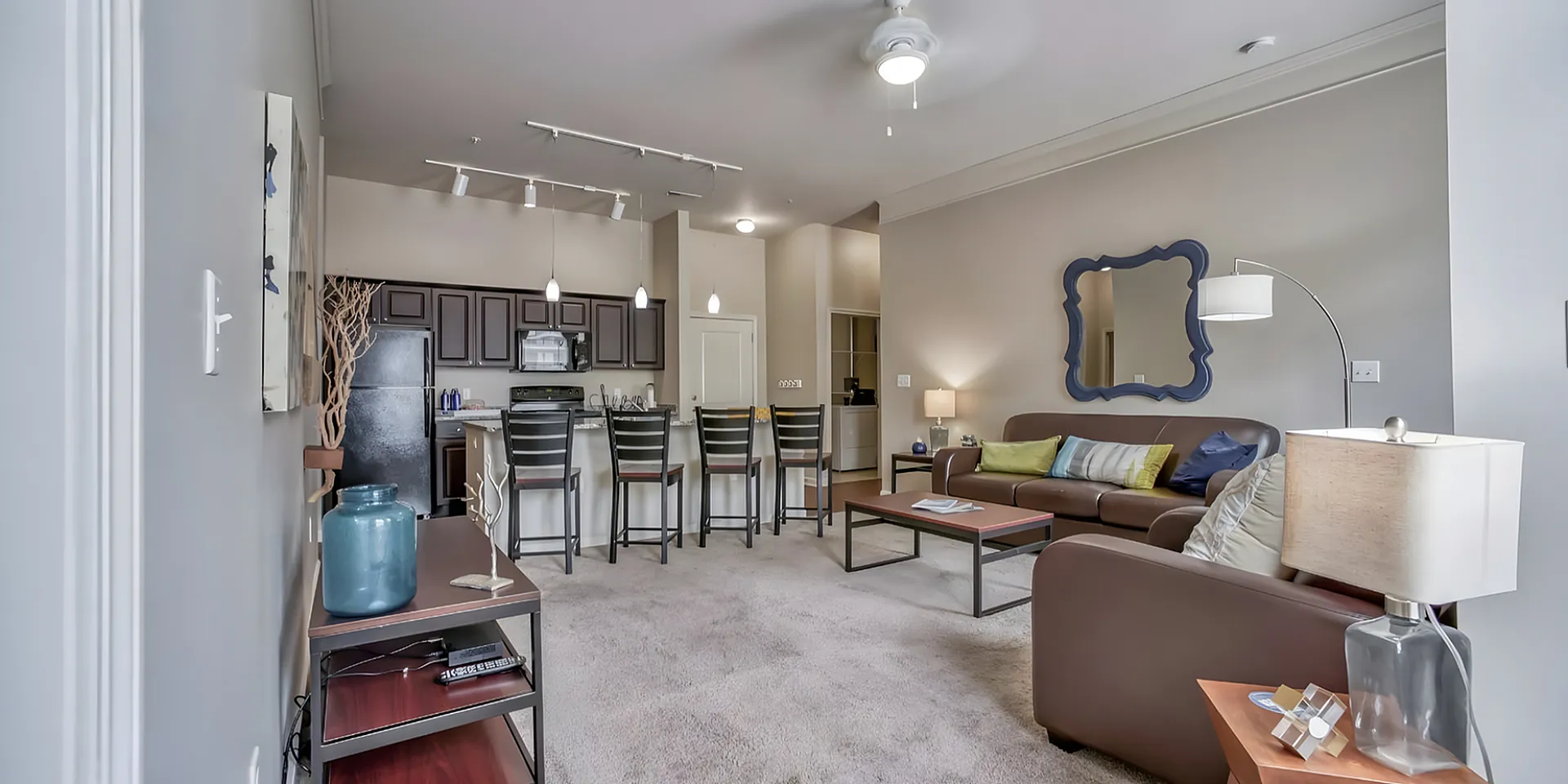 Modern open-concept living space with elegant design, featuring a cozy seating area and sleek kitchen with bar seating.