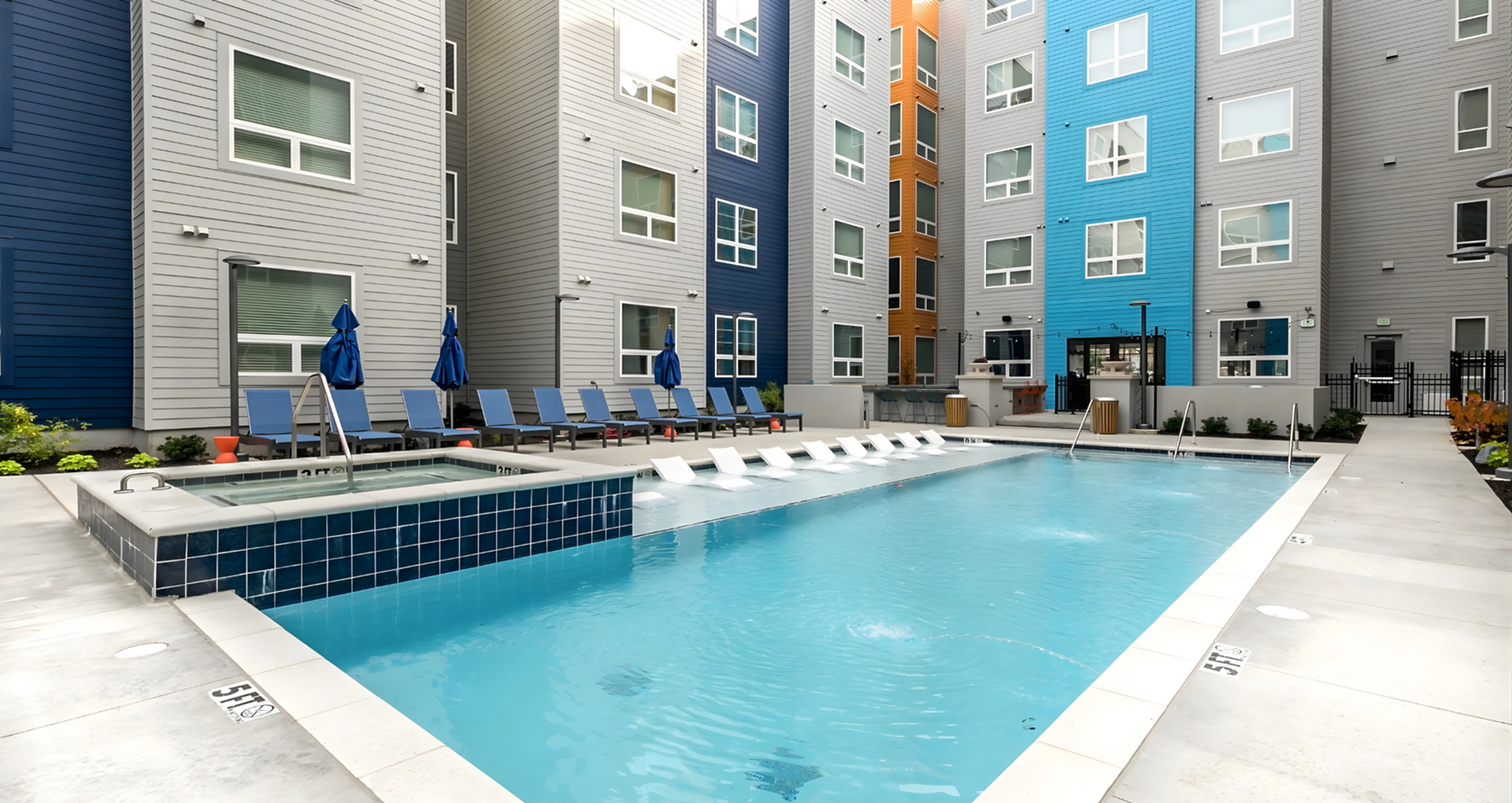 Contemporary apartment complex with vibrant facades featuring a stunning outdoor pool area, complete with stylish lounge chairs and modern landscaping.