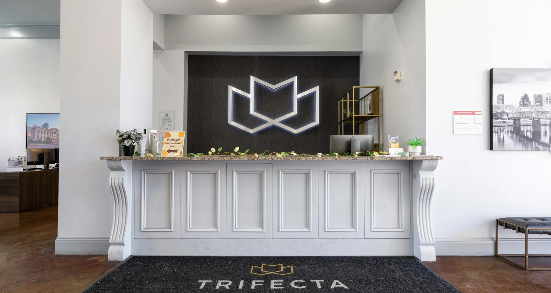 Modern reception area showcasing sleek design with illuminated logo, elegant marble counter, and inviting decor.