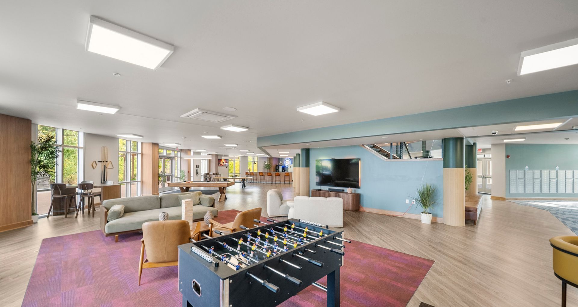 Modern communal lounge featuring stylish seating, a foosball table, and a large TV, perfect for socializing and relaxation.