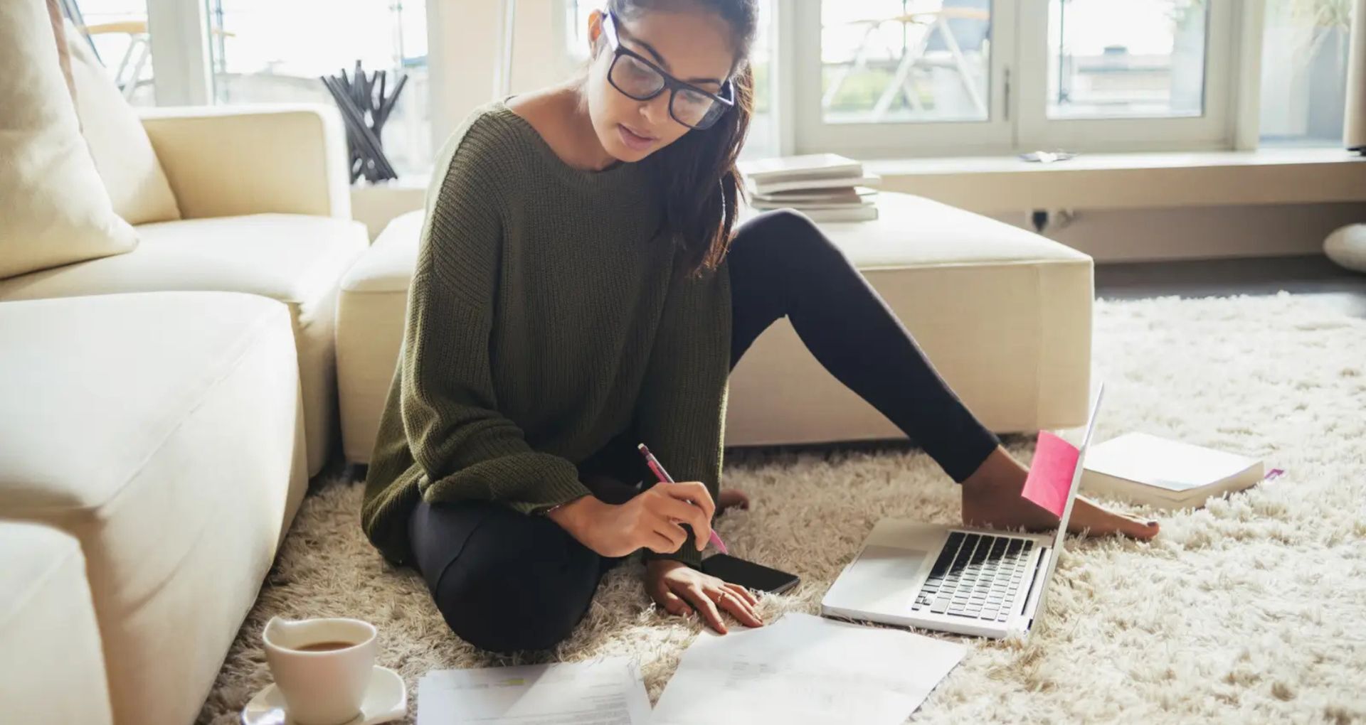 Cozy apartment living room with plush carpeting, natural light through large windows, and a comfortable, relaxed atmosphere perfect for working or unwinding.