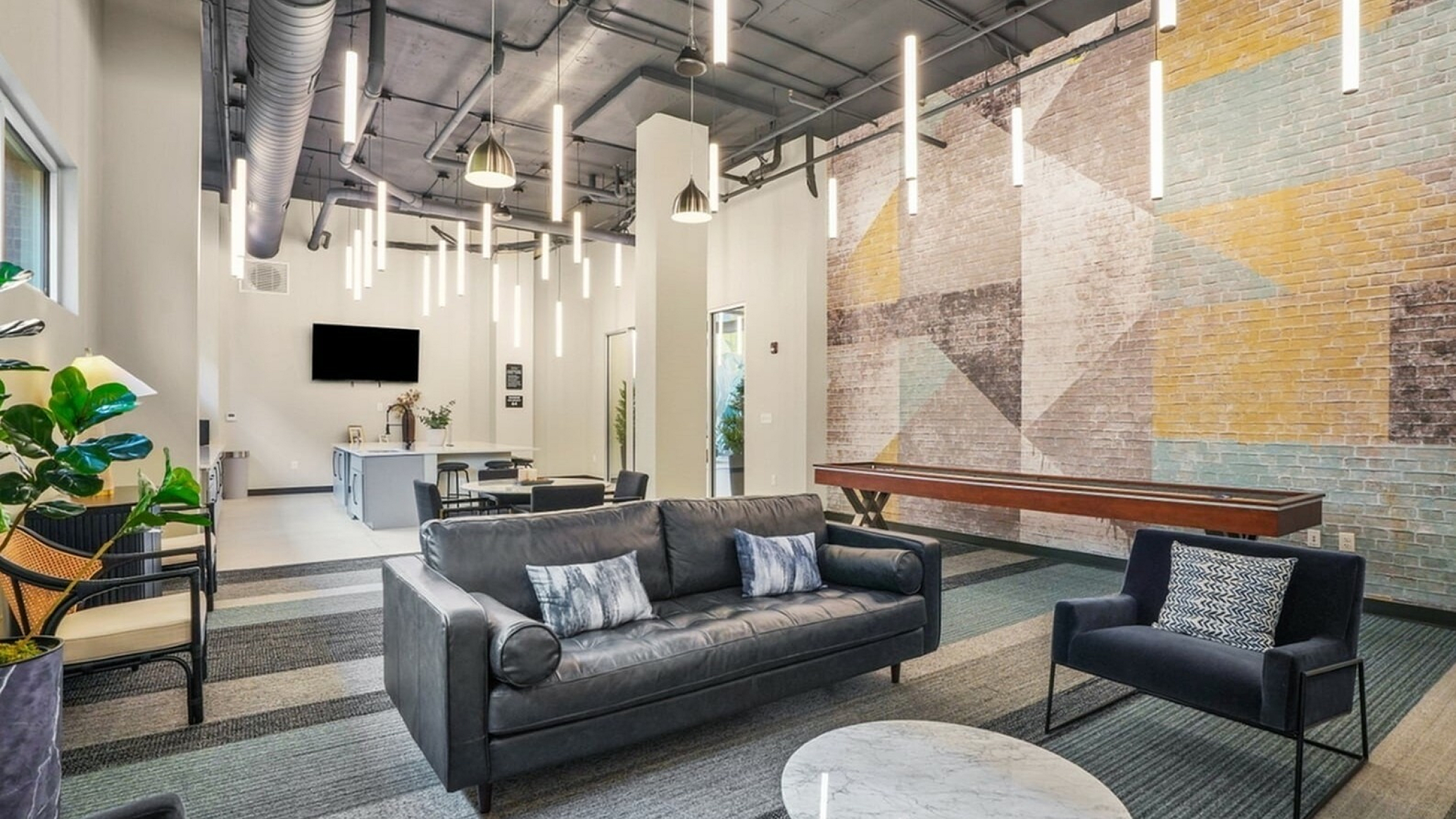 Modern lounge area with stylish sofas, vibrant geometric wall art, and sleek hanging lights creating an inviting atmosphere.